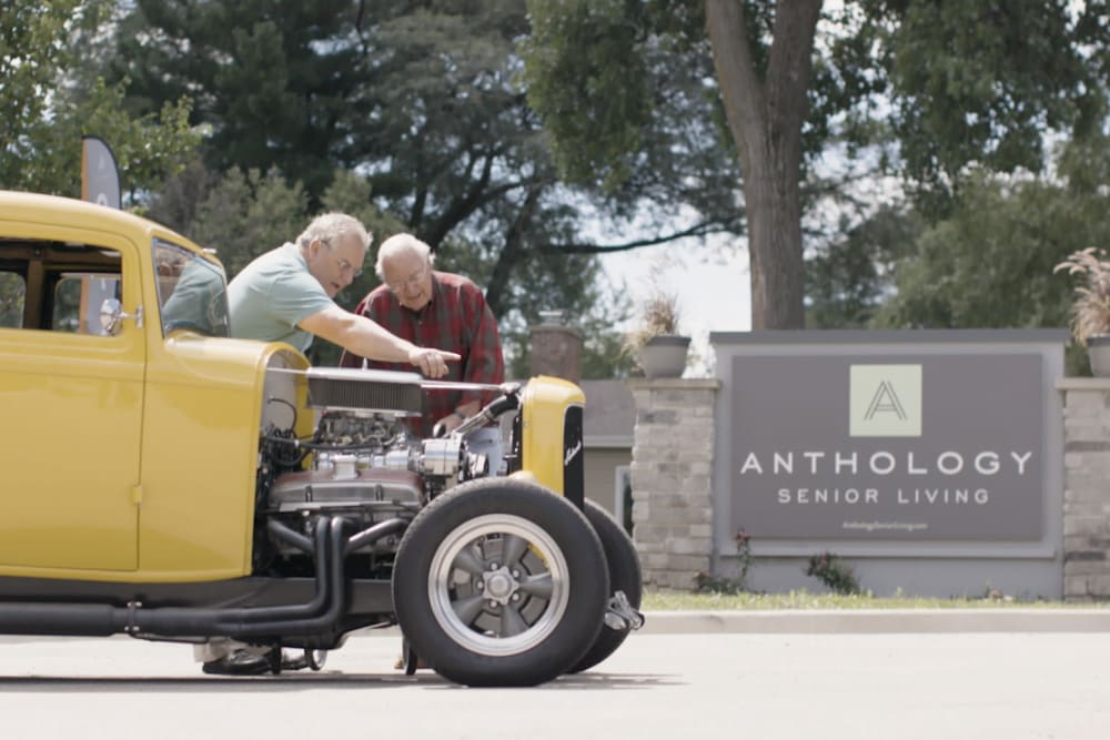 Two residents working on an old-school car at a Anthology Senior Living location